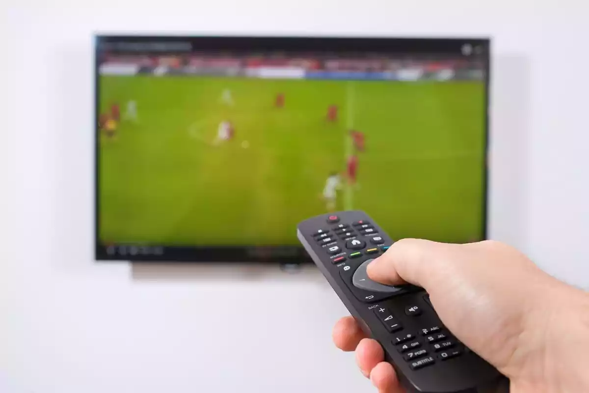 Un mando encendiendo la televisión durante un partido de futbol